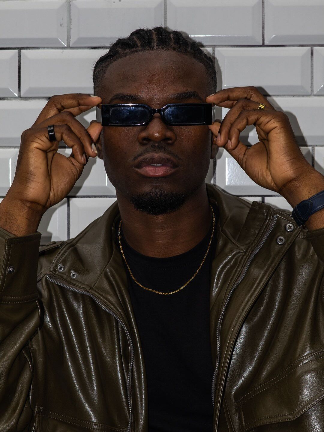 Graël ajustant des lunettes noires, veste de cuir brun