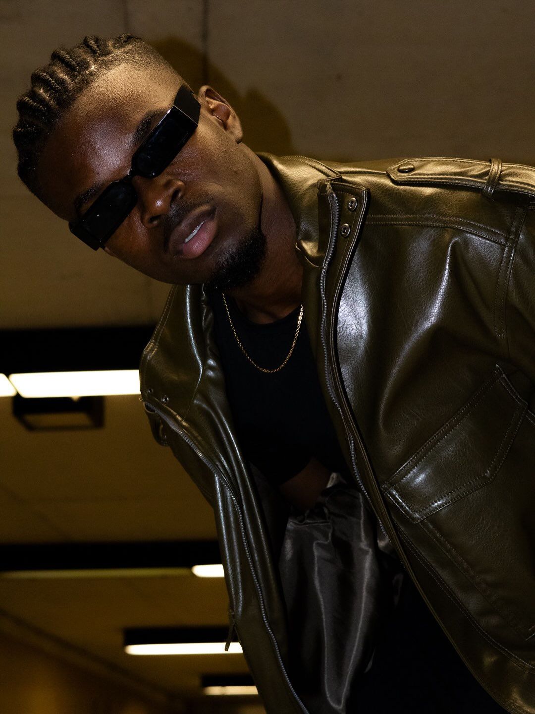 Graël penché vers l’objectif, lunettes noires et veste de cuir brun