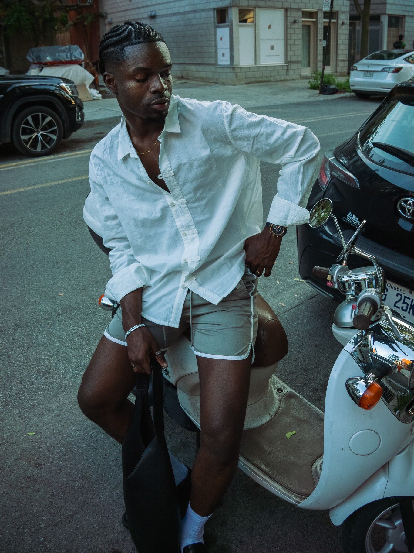 Graël en chemise blanche appuyé sur un scooter, rue de Montréal
